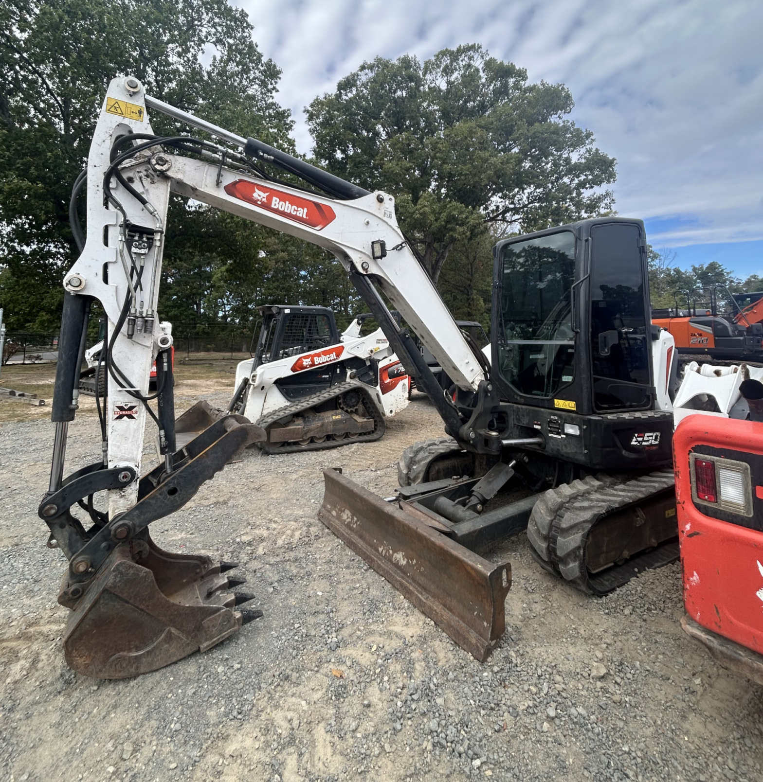 Used Bobcat compact excavator with enclosed cab, rubber tracks, front dozer blade, and digging bucket at an outdoor equipment lot.